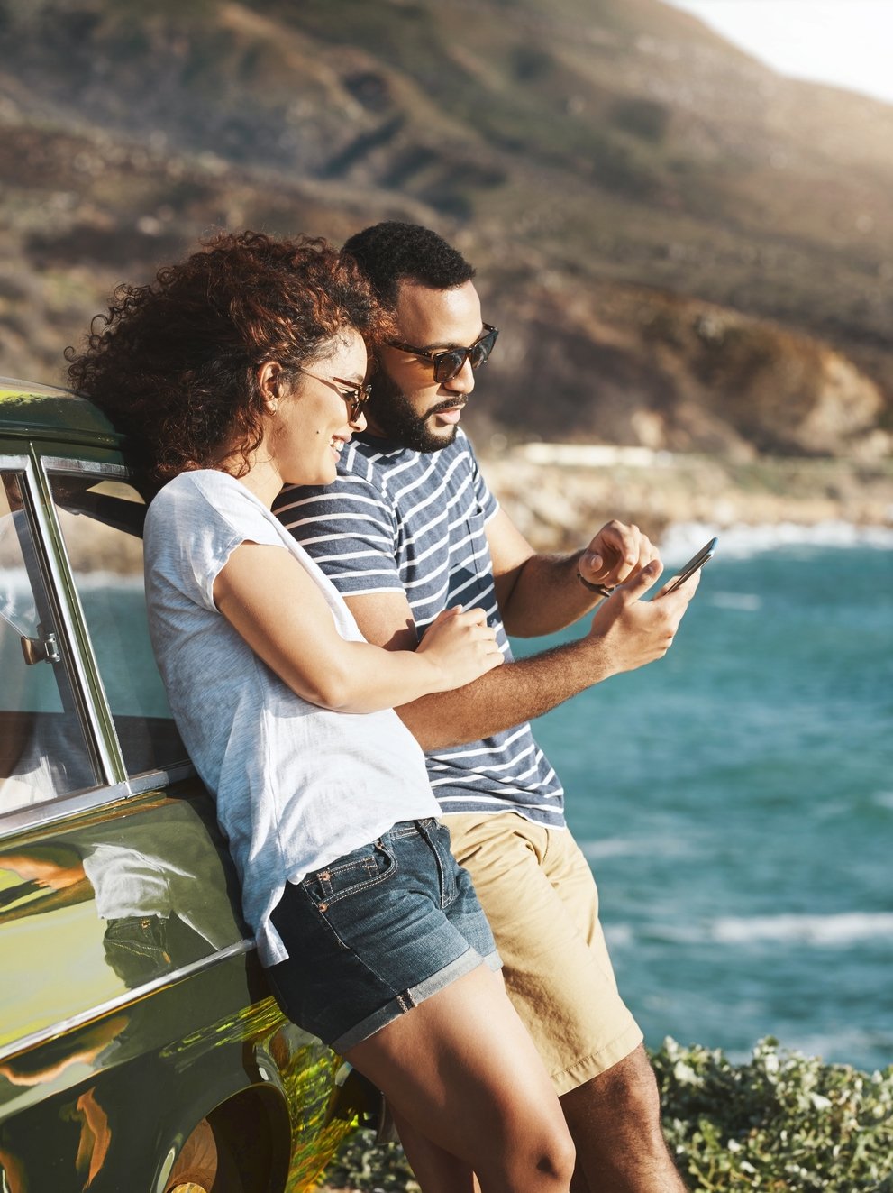 Shot of a young couple using a mobile phone on a road trip